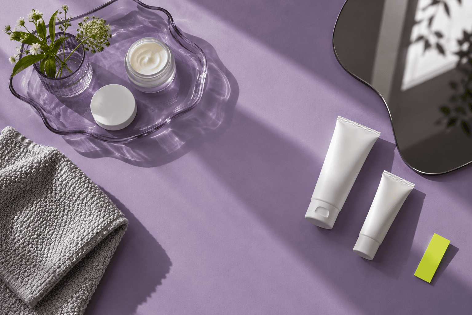 A lavender skincare tray, plain tubes, a graphite mirror and folded silver towel