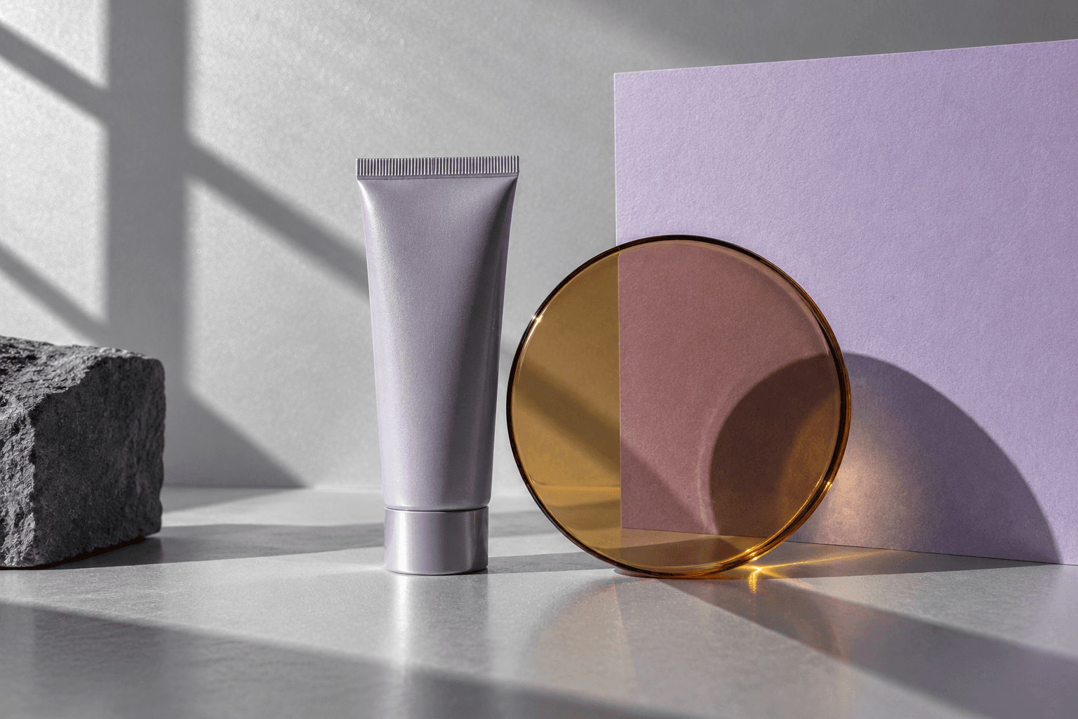 Small unmarked tube and a translucent amber glass circle on lavender paper